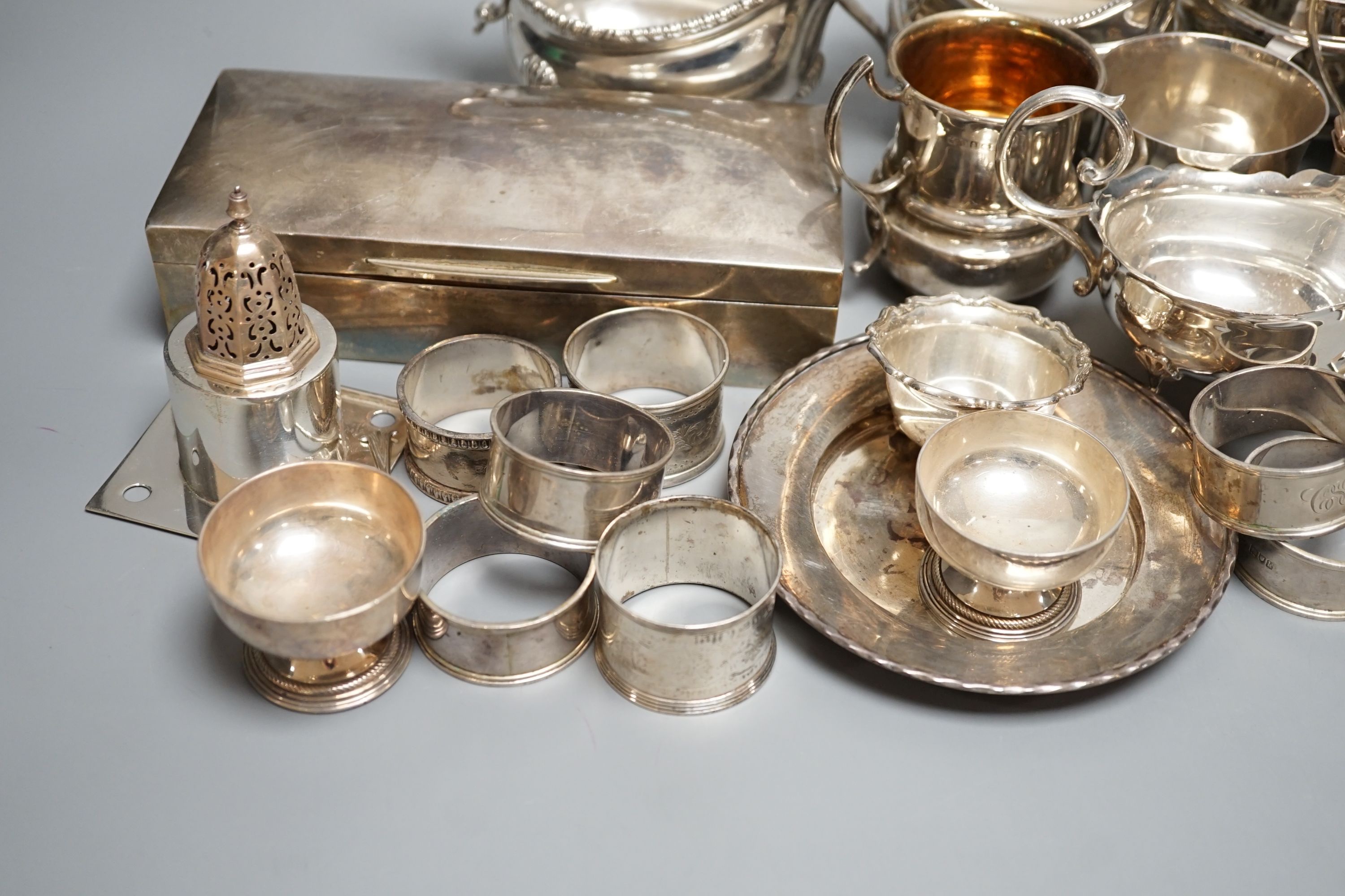 A quantity of assorted mainly 20th century sundry silver including three cream jugs, two silver sauceboats, two small mugs, pair of pepperettes, cigarette box, two match sleeves, pair of salts, seven napkin rings, two sc